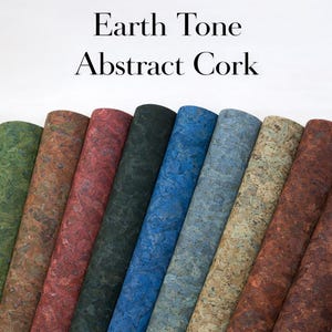 May include: A collection of rolled cork sheets in various earth tone colors. The cork sheets are in shades of green, brown, red, dark green, blue, and tan. The text "Earth Tone Abstract Cork" is displayed at the top of the image.