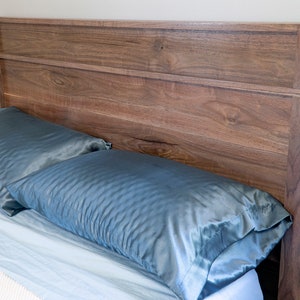 Peut inclure: Une t&ecirc;te de lit en bois avec une finition brun clair et un design simple. La t&ecirc;te de lit a deux lattes horizontales et est plac&eacute;e contre un mur blanc. Deux oreillers en satin bleu sont sur le lit devant la t&ecirc;te de lit.