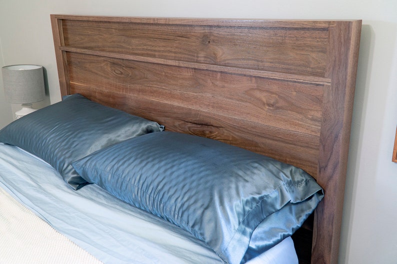 Peut inclure: Une t&ecirc;te de lit en bois avec une finition brun clair et un design simple. La t&ecirc;te de lit a deux lattes horizontales et est plac&eacute;e contre un mur blanc. Deux oreillers en satin bleu sont sur le lit devant la t&ecirc;te de lit.