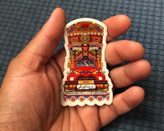 May include: A colorful sticker of a decorated truck with the Urdu text "Waseeraki" on the front bumper.