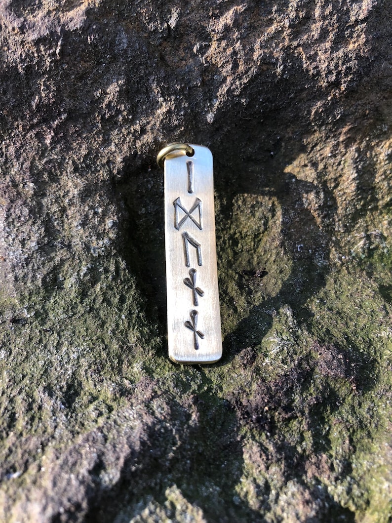 May include: A silver metal keychain with a vertical row of five Norse runes engraved on it. The runes are: Isa, Nauthiz, Jera, Ansuz, and Dagaz.