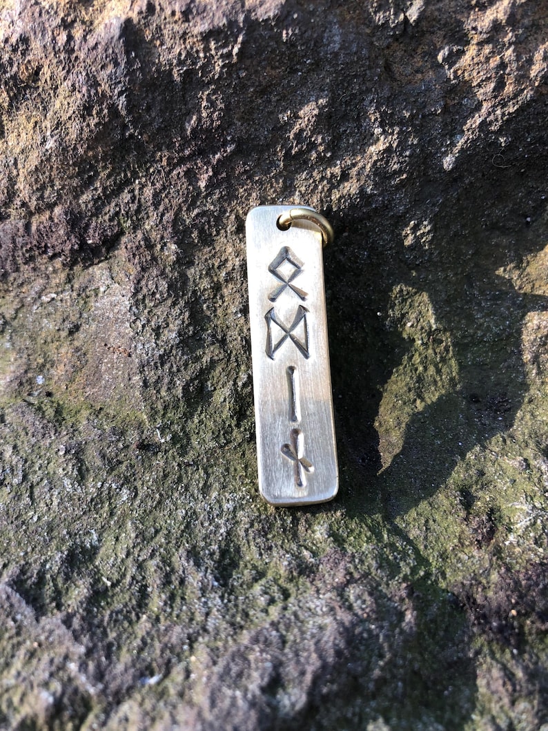 May include: A silver-colored metal keychain with a rectangular tag engraved with a series of runes.