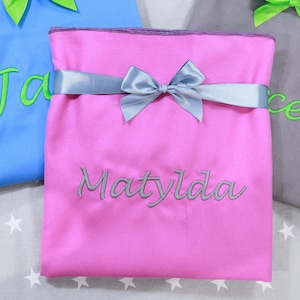 May include: Three fabric gift bags with green and blue ribbons. The bags are personalised with the names "Jacob", "Matylda", and "Rachel" in green and grey embroidery.