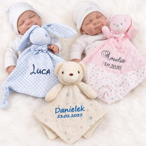 Könnte beinhalten: Drei Plüsch-Schmusetücher mit Tierköpfen: ein blauer Hase mit Punkten und der Stickerei 'Luca', ein rosa Bär mit Sternen und 'Amelia 13.11.2020' sowie ein cremefarbener Bär mit Sternen und der Stickerei 'Danielek 23.02.2022'.