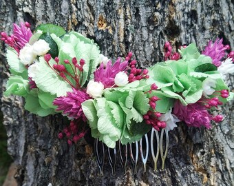 Side headdress of preserved flowers in mint green and fuchsia tones.