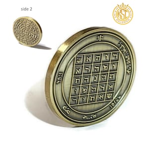 Op de afbeelding: Een gouden metalen munt met een vierkant raster van Hebreeuwse letters in het midden. De munt heeft een verhoogde rand en een cirkelvormige inscriptie rond de rand. De inscriptie luidt "King Solomon".
