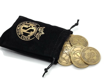May include: A black velvet pouch with gold lettering that reads "King Solomon Coin" is open, revealing a set of seven gold-colored metal coins with intricate designs.