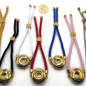 May include: A collection of adjustable bracelets with gold-colored metal accents and colorful rope cords. Each bracelet features a round, gold-colored charm with the text "KING SOLOMON COIN". The cords are in various colors, including yellow, black, white, red, blue, pink, and gold.