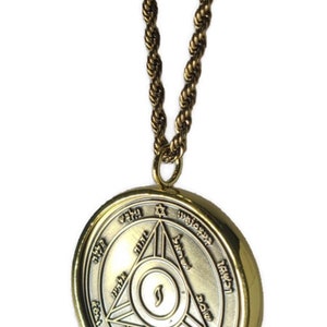 May include: A gold chain necklace with a round pendant featuring a silver-toned design with Hebrew text and a star of David. The pendant is surrounded by a gold rim.