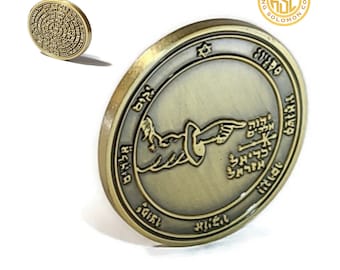May include: A gold-colored metal coin with a design of a hand pointing to a star with Hebrew text around the edge. The text reads "King Solomon Coin".