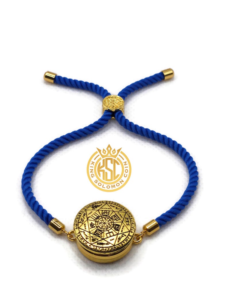 May include: A gold-colored bracelet with a circular pendant featuring intricate engravings. The bracelet has a blue rope-like band with gold-colored accents. The pendant has a detailed design with symbols and text. The bracelet is adjustable.
