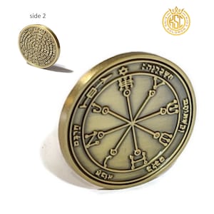 Puede incluir: Una moneda de metal de color dorado con un diseño circular. El anverso presenta una estrella de David en el centro con seis radios que irradian hacia afuera. Cada radio tiene una letra hebrea y un símbolo. El reverso presenta un diseño circular con texto hebreo.