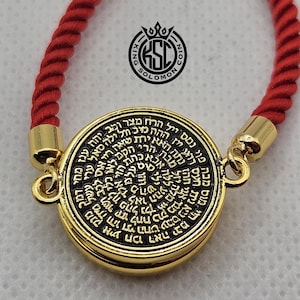May include: A gold-colored pendant with black text, attached to a red rope bracelet. The pendant has a circular design with Hebrew text. The bracelet has gold-colored clasps. The logo "KING SOLOMON COIN" is visible.