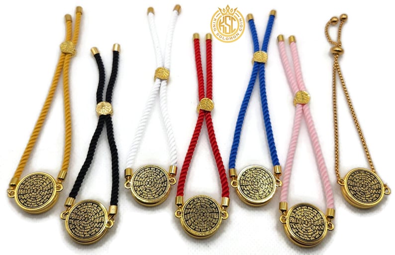 May include: A collection of adjustable bracelets in various colors, including gold, black, white, red, blue, and pink. Each bracelet features a gold-colored circular pendant with an intricate design and a sliding knot closure.