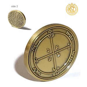 Può includere: Una moneta dorata con un designo circolare che presenta lettere ebraiche e una stella di David. La moneta è incisa con "King Solomon Coin" sul bordo.