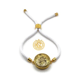 May include: A gold-colored bracelet with a circular pendant featuring intricate designs. The pendant is connected to a white rope-like band with gold-colored accents. The bracelet is adjustable and has a logo that says "King Solomon Coin".
