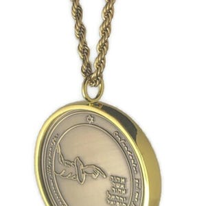 May include: Gold chain necklace with a round pendant featuring a Hebrew inscription and a stylized image of a hand pointing upwards. The pendant has a gold rim.