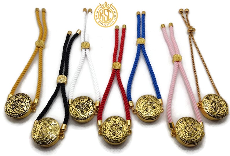May include: An assortment of adjustable bracelets with gold-colored circular pendants and rope or chain straps in various colors, including yellow, black, white, red, blue, and pink. The pendants have an intricate design.