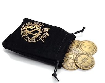 May include: A black velvet pouch with a gold logo that reads "King Solomon Coin" and a gold drawstring. The pouch is open and spilling out six gold coins with intricate designs.