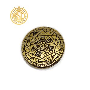 May include: A gold-colored coin with intricate engravings of symbols and text. The coin features a central design surrounded by a star-shaped pattern and inscriptions. The coin has a raised edge and a detailed surface.