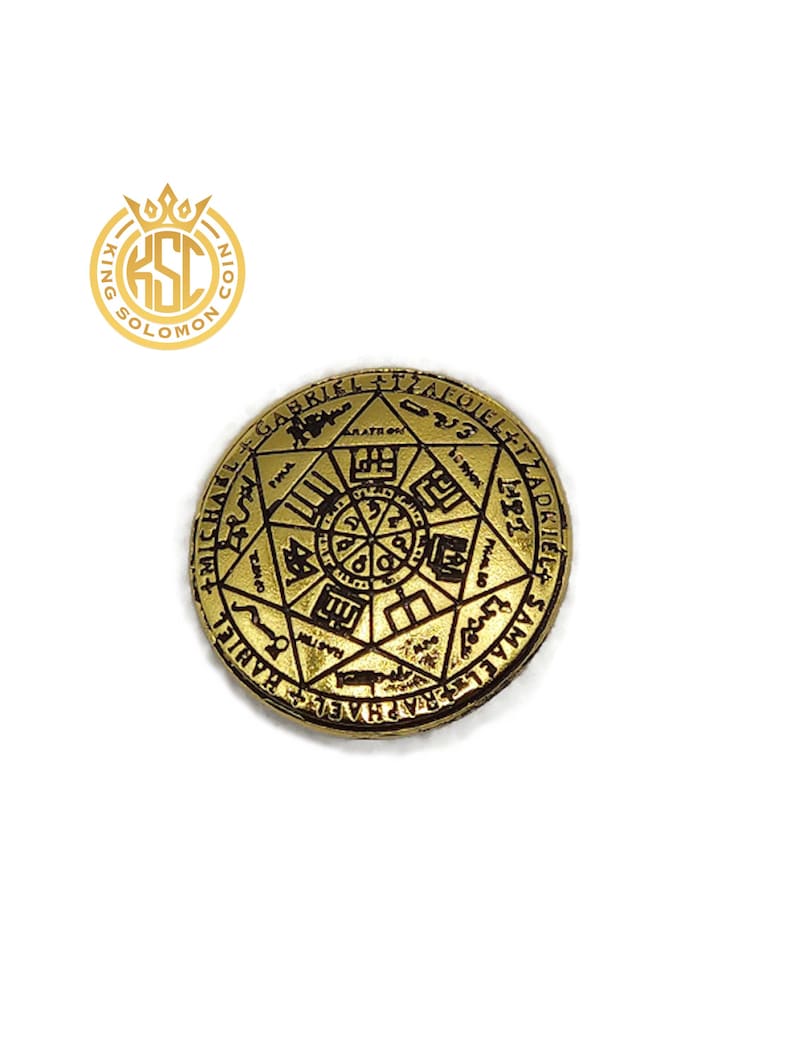 May include: A gold-colored coin with intricate engravings of symbols and text. The coin features a central design surrounded by a star-shaped pattern and inscriptions. The coin has a raised edge and a detailed surface.