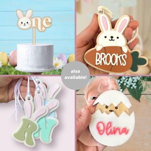 May include: A set of three wooden Easter bunny ornaments with personalized names. The ornaments are painted in pastel colors and feature a bunny holding a carrot. The names "Brooks", "Olivia", and "Ryan" are written on the ornaments.