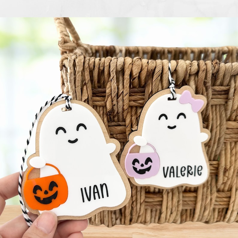 May include: Two wooden ghost-shaped Halloween trick-or-treat tags with a pumpkin bucket and the names "Ivan" and "Valerie" written on them.