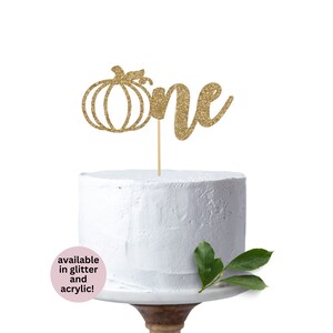 May include: Gold glitter pumpkin and the word "one" cake topper. Available in glitter and acrylic.