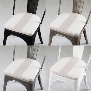 May include: Four metal chairs with seat cushions. Each cushion is white with a light pink stripe down the center. The chair frames are black, silver, gray, and white. The chairs are designed for indoor use.