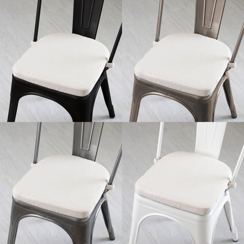 May include: Four metal chairs in black, gray, and white, each with a square, off-white cushion. The chairs have a classic industrial design with a curved back and a seat that is approximately 16 inches wide.
