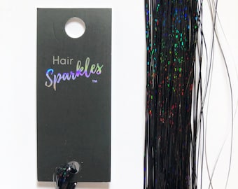 May include: Black hair tinsel with iridescent rainbow sparkles. The tinsel is packaged with a black tag that reads "Hair Sparkles TM".