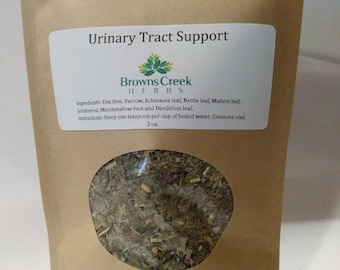 May include: A brown paper bag with a clear window showing a blend of dried herbs. The bag is labelled "Urinary Tract Support" and "Browns Creek Herbs". The ingredients are listed as: Uva Ursi, Yarrow, Echinacea leaf, Nettle leaf, Mullein leaf, Goldenrod, Marshmallow root and Dandelion leaf. The instructions are to steep one teaspoon per cup of boiled water and consume cool. The bag is 2 oz.
