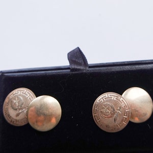 May include: A pair of gold cufflinks in a black velvet box. The cufflinks are round and have a design of a crescent moon and star.