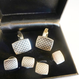 May include: A set of five silver cufflinks in a black box. The cufflinks have a geometric pattern.