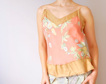 May include: A pink and brown floral print sleeveless top with a ruffled hem. The top is worn with a light blue and green patterned skirt.