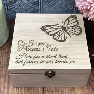 May include: A wooden box with a butterfly design and the inscription "Our Gorgeous Princess Solo Here for a short time but forever in our hearts xx".