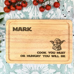 May include: A personalised wooden chopping board with the name "Mark" engraved on it. The board also features a Star Wars Yoda character and the text "Cook you must or hungry you will be".