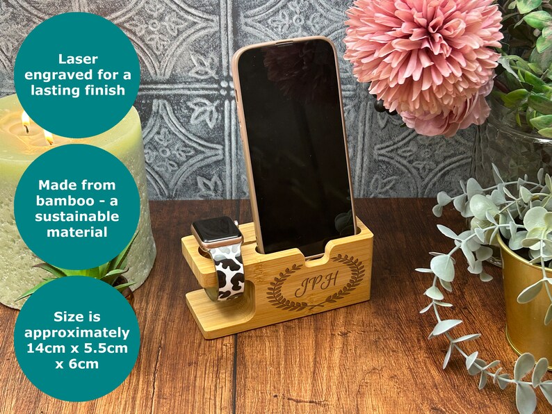 May include: A wooden phone and watch stand with a personalised inscription "IPH" in a laurel wreath design. The stand is made from bamboo and measures approximately 14 cm x 5.5 cm x 6 cm.