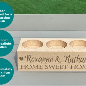 May include: A wooden candle holder with three tealight candle wells. The holder is engraved with the text "Roxanne & Nathan HOME SWEET HOME" and two hearts.