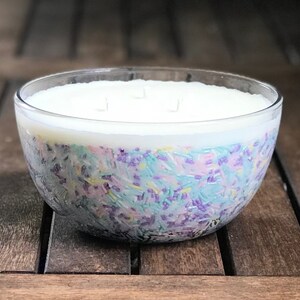 以下が含まれることがあります： 白い上層と、ろうの中に埋め込まれたカラフルなスプリンクルが入った、大きな透明なガラスボウルキャンドル。スプリンクルは、パステルブルー、パープル、イエローの色合いです。キャンドルには3つの芯があります。