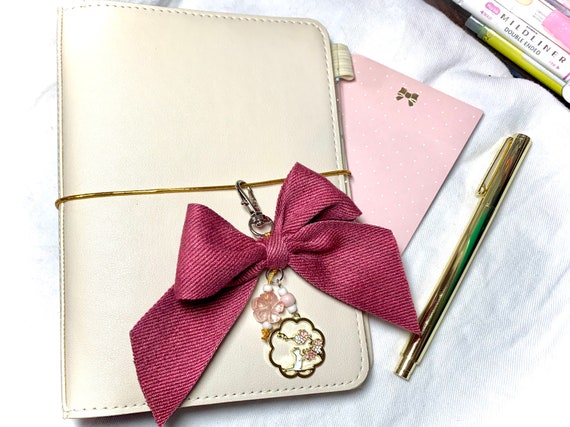 Opulent bow charm with soft cotton ribbon, enamel cat pendant, and natural carved stone blossom bead to embellish your planner or bag!