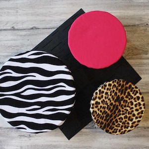 May include: Three round fabric bowl covers. One is black and white zebra print, one is brown and tan leopard print, and one is solid pink.