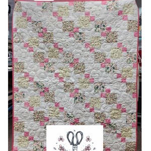May include: A rectangular baby quilt featuring a patchwork design of white, yellow, and floral patterned squares accented with small pink squares. The quilt has a pink border and circular quilting patterns. Text at the top reads D9P - The Baby Quilt.