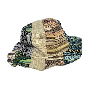 May include: A bucket hat constructed from various fabric panels featuring a mix of textures and patterns. The design includes sections of beige herringbone, black and white stripes, and multi-colored woven textiles in shades of blue, green, and red.