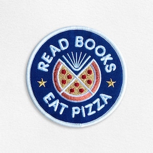 May include: A blue and white embroidered patch with the text "Read Books Eat Pizza" and a stylized image of a pizza slice with a book inside.