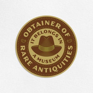 May include: A circular sticker with a brown and gold color scheme. The sticker features the text "OBTAINER OF RARE ANTIQUITIES" around the edge, with "IT BELONGS IN A MUSEUM" in the center, and an illustration of a fedora.