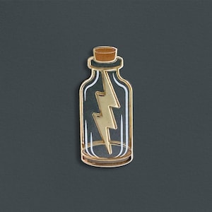 Op de afbeelding: Gouden metalen pin van een glazen fles met een kurkstop en een gouden bliksem erin.