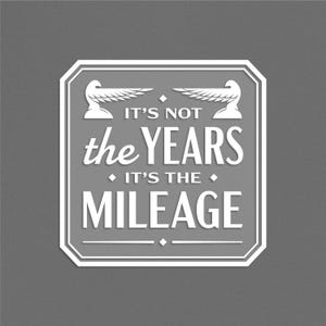 May include: White graphic with a vintage design featuring two stylized birds with wings spread. The text reads "It's not the years it's the mileage".
