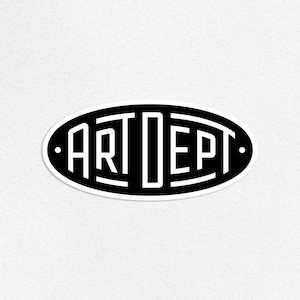May include: An oval sticker in black and white, featuring the text "ART DEPT". The words are in a bold, geometric font, with white lettering on a black background. The sticker has a white border and a minimalist aesthetic.
