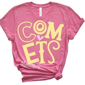 May include: Pink t-shirt with the words "Comets" in yellow with a pink heart in the middle of the "O". The text "My Designs in the Chaos" is printed in black at the bottom of the shirt.